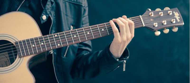 chitarra-in-primo-piano-suonata-da-ragazzo-con-giacca-di-pelle