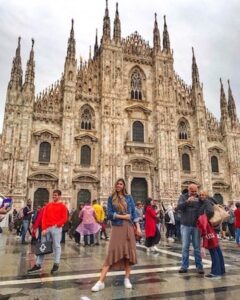 ragazza colombiana con vestito marrone e giacca blu davanti a duomo di Milano